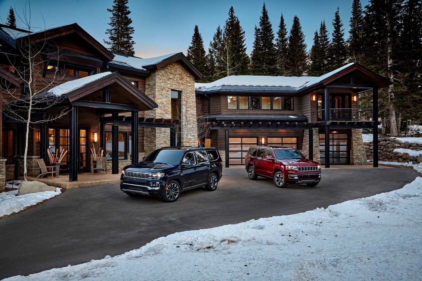 The Jeep Grand Wagoneer to the left of the 2022 Wagoneer parked in the courtyard of a chalet during the winter season