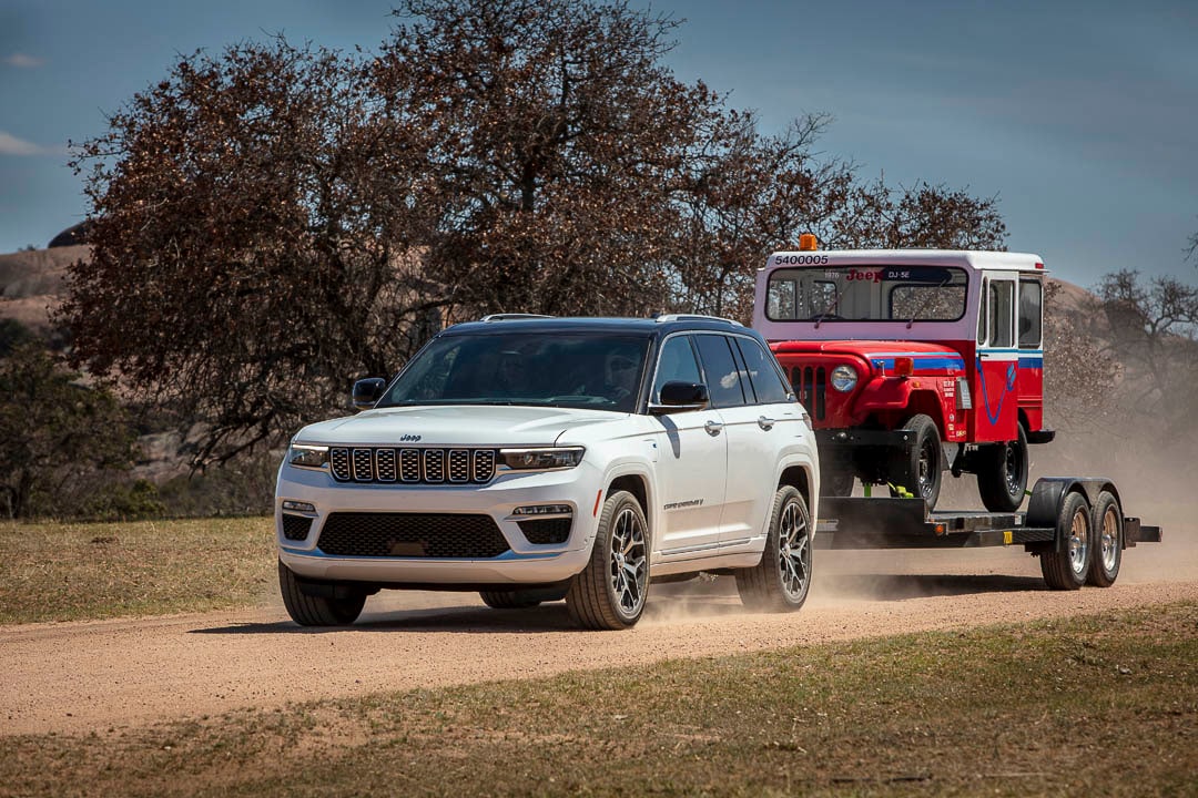 three quarter front view of the 2022 Jeep Grand Cherokee 4xe towing a vintage Jeep
