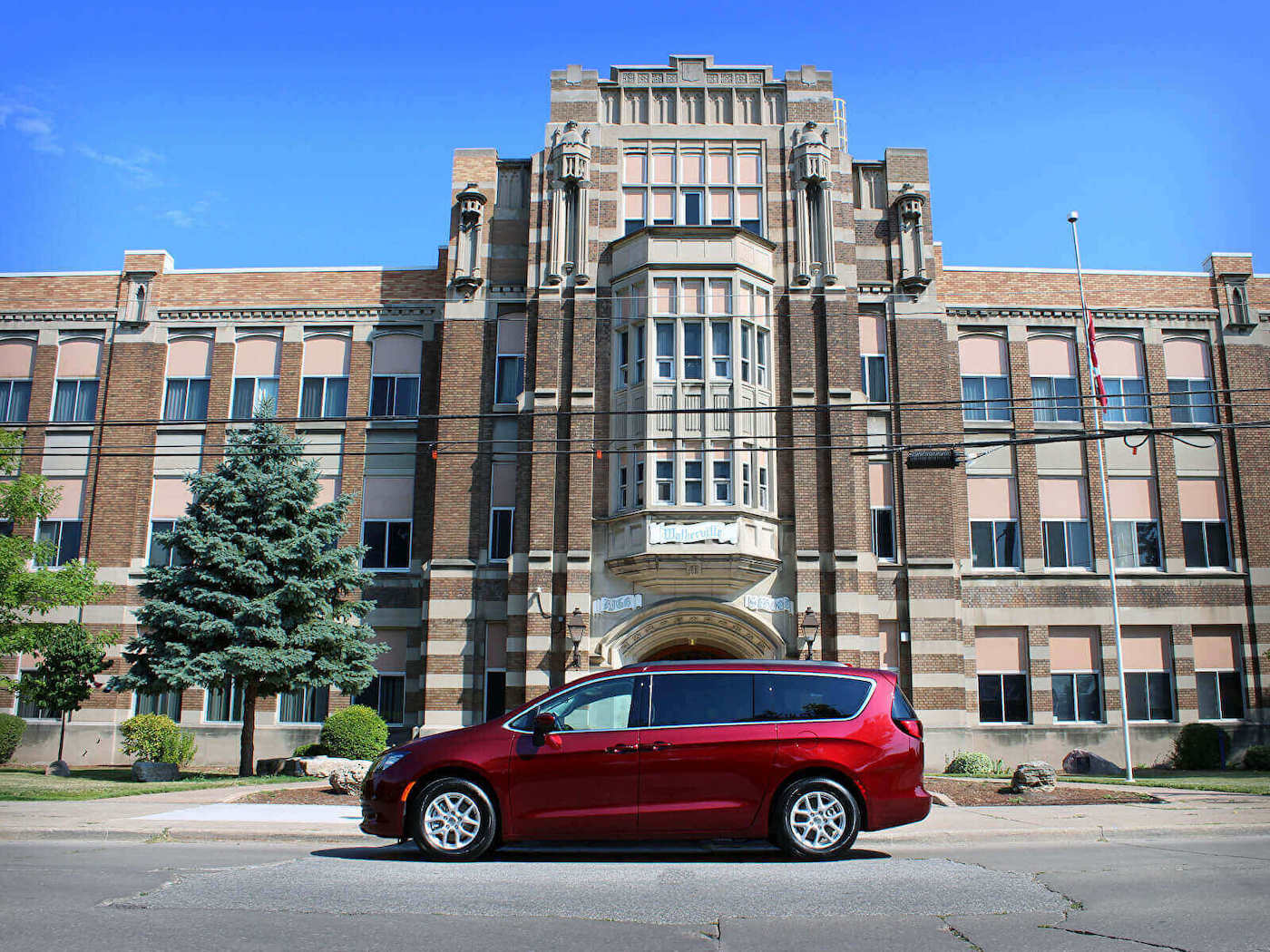 Vue latérale d'une mini-fourgonnette Chrysler Grand Caravan garée devant un école
