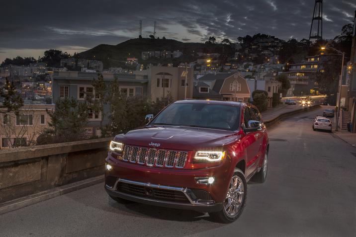 Jeep Grand Cherokee Summit 2015 rouge garé sur une rue en ville vers la fin du coucher du soleil