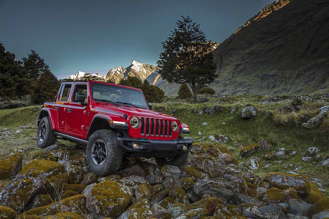 Vue 3/4 avant d'un Jeep Wrangler Rubicon 2021 rouge garé sur des rochers en nature