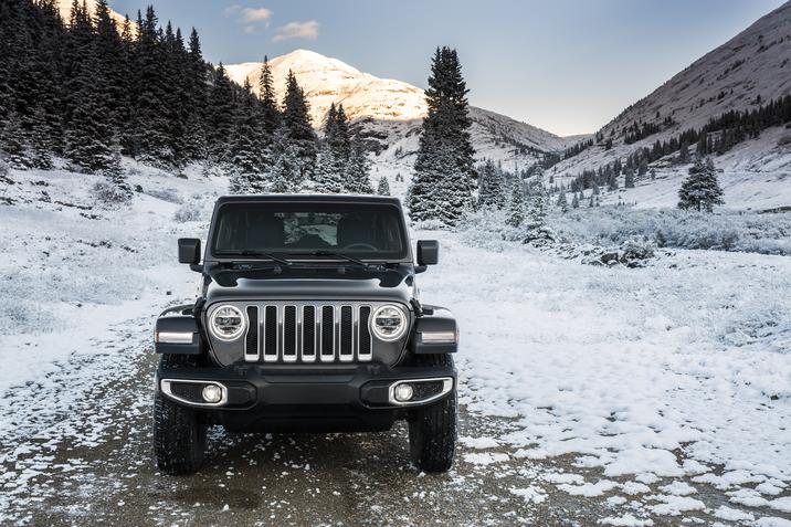 Jeep Wrangler Sahara 2019 gris foncé garé sur un chemin de terre semi-glacé dans la forêt pendant la saison hivernale 