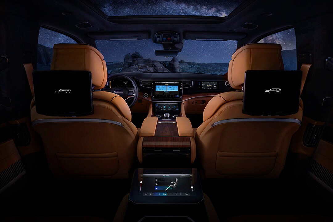 Habitacle d'un Jeep Grand Wagoneer 2022 incluant les écrans arrières des passagers pendant la nuit