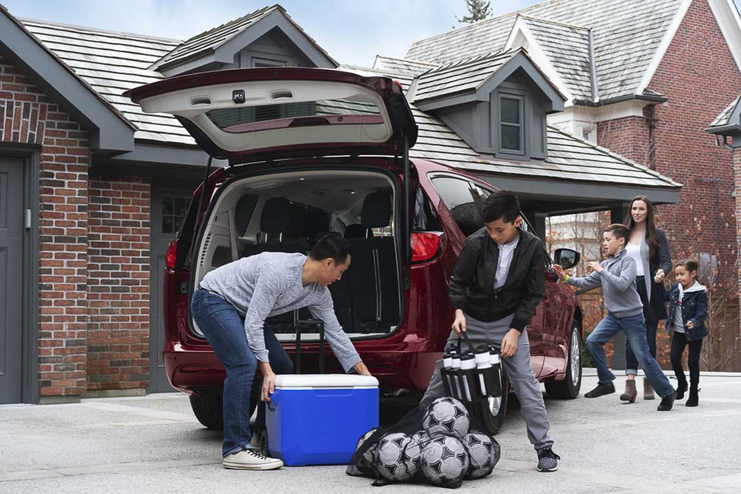 Famille chargeant leur glacière et ballons de soccer dans l'espace de chargement de la Chrysler Grand Caravan 2021