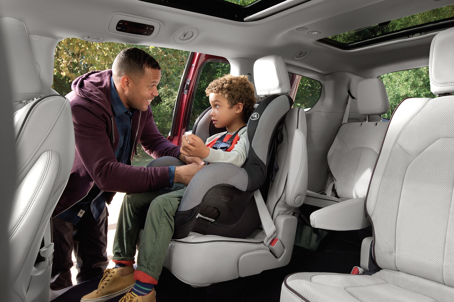 père attachant la ceinture de sécurité de son enfant dans la Chrysler Pacifica Hybride 2020