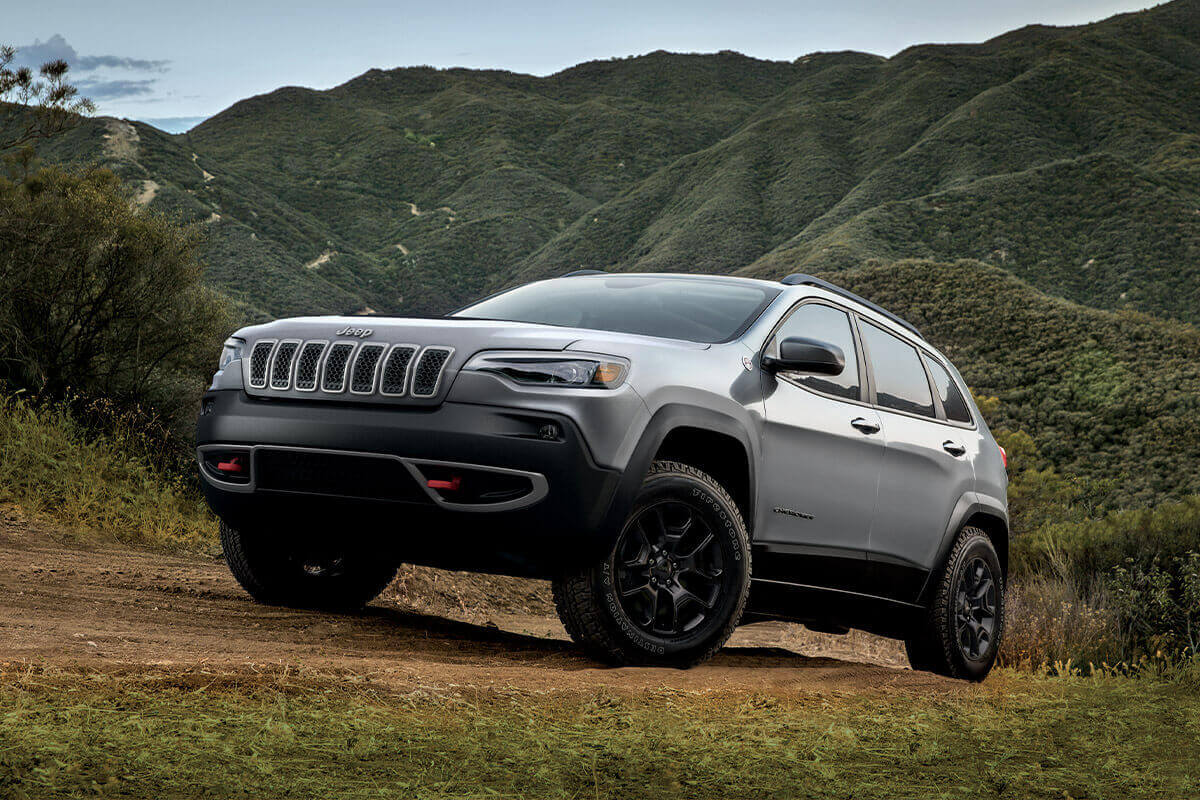 Front 3/4 view of a sting grey 2022 Jeep Cherokee parked on a mountain road