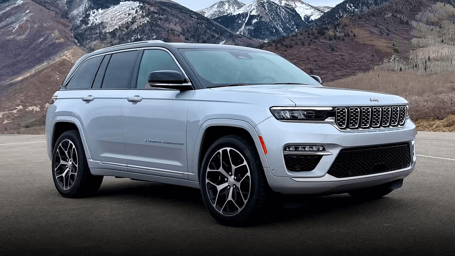 Exterior shot of a Jeep Grand Cherokee parked in a parking lot with mountains in the background.