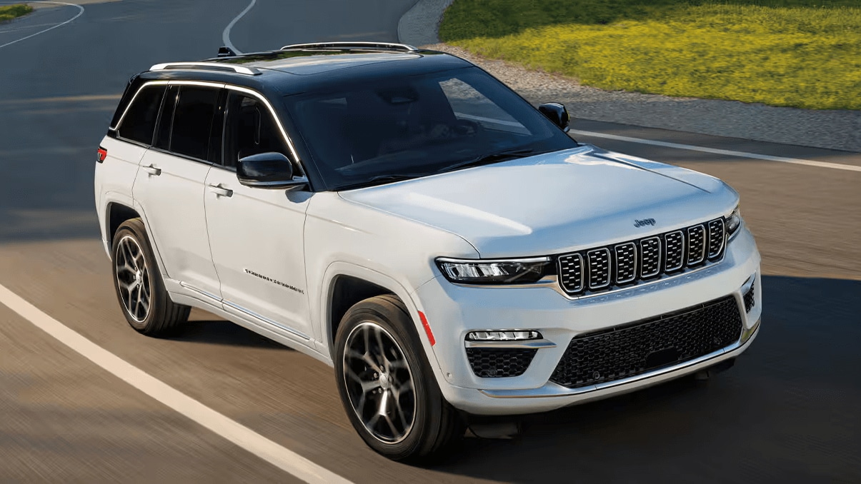 A white Jeep Grand Cherokee driving down a road