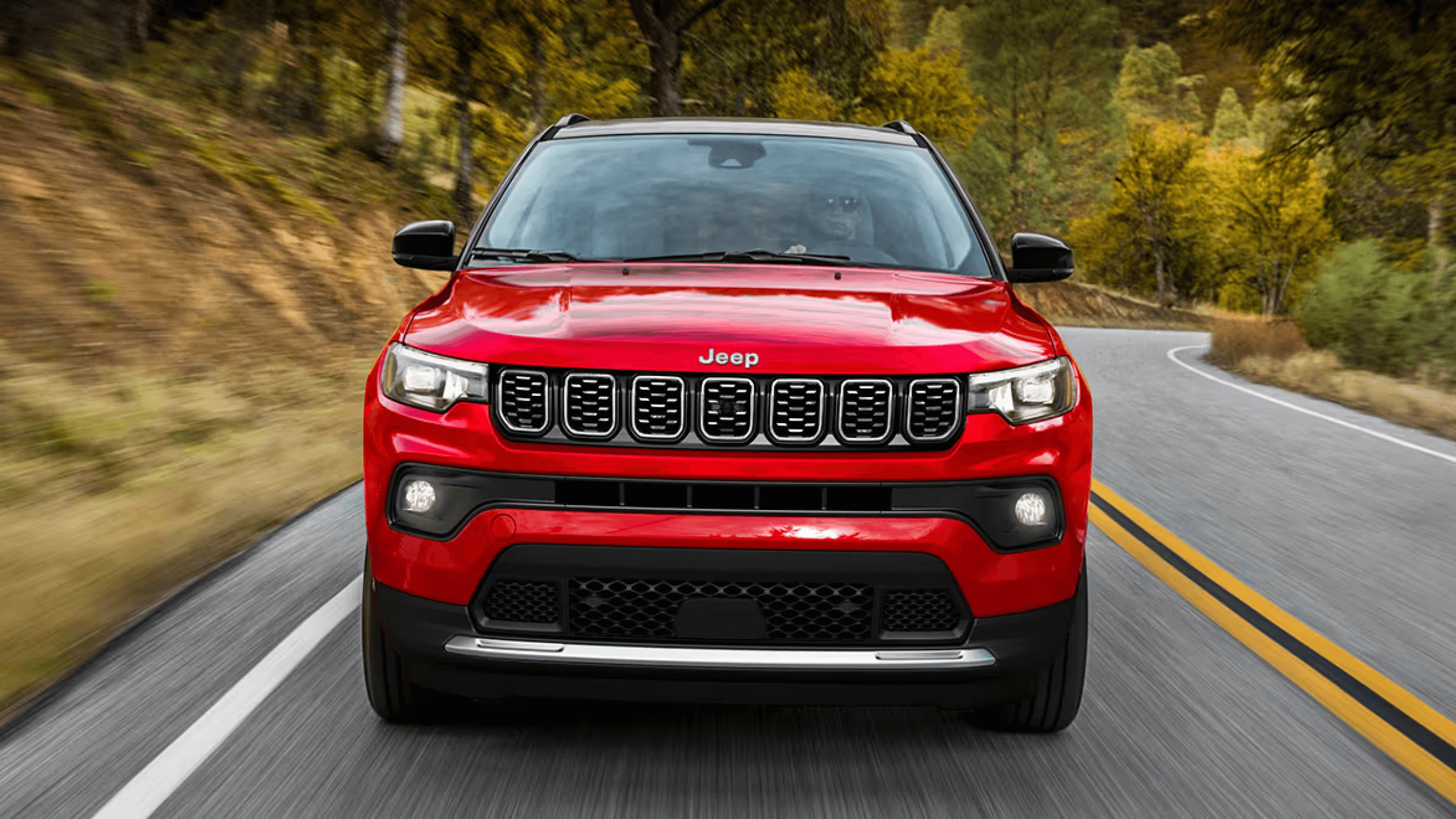 Learn about the exterior design & features of the Jeep Compass SUV Exterior shot of a red Jeep Compass SUV driving down the road