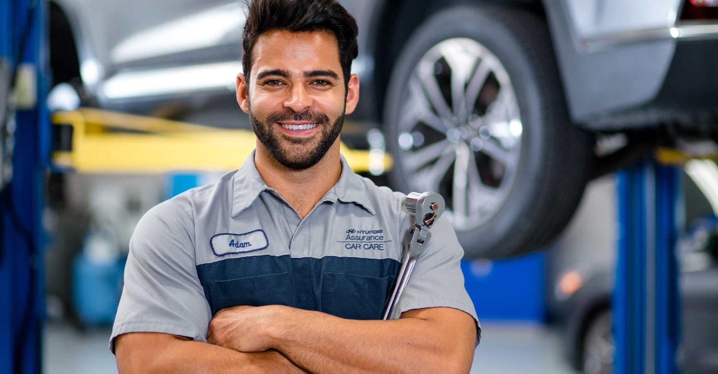 Hyundai mechanic smiling in front of a car lift