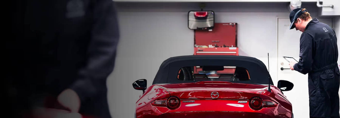 Mazda Mechanic standing behind a Miata