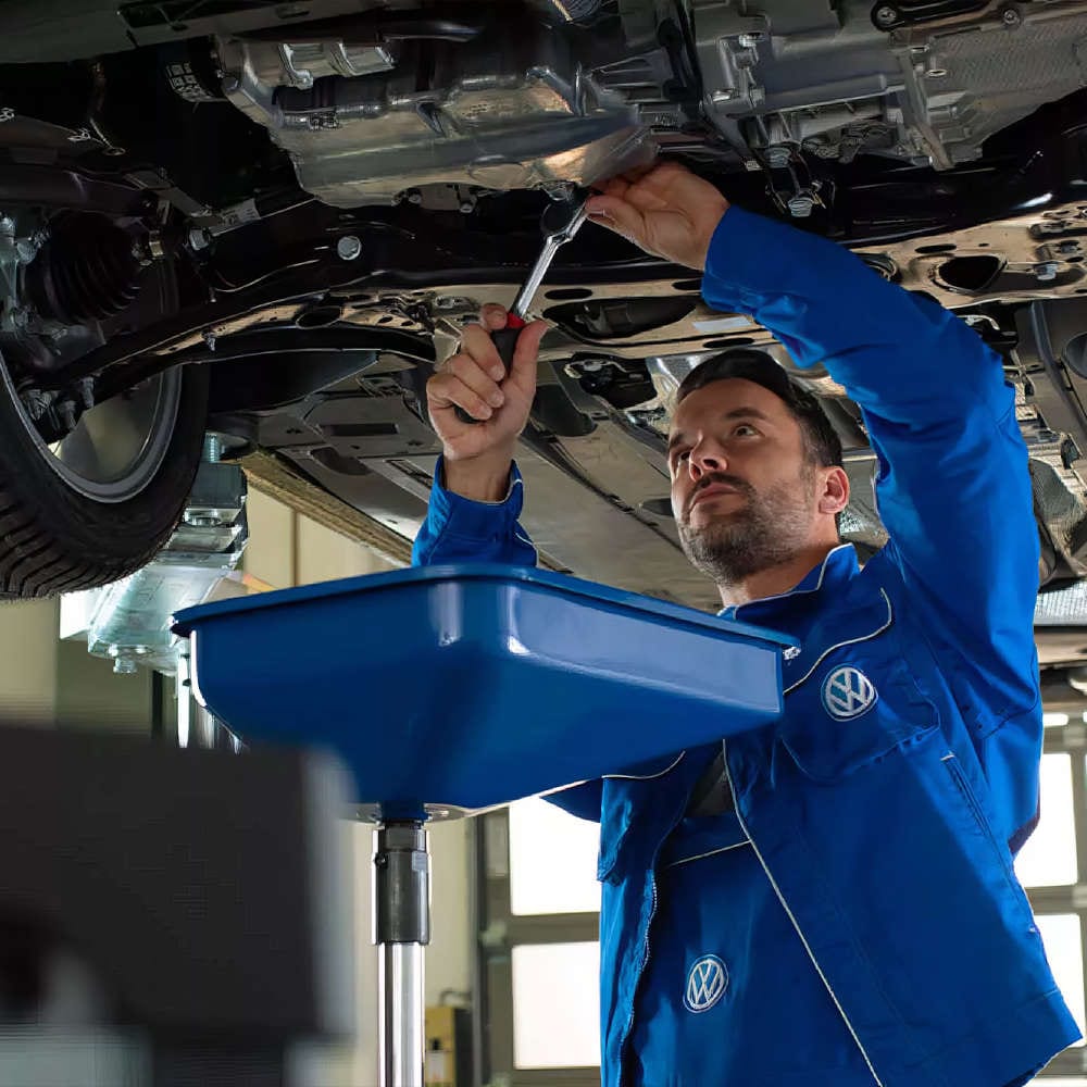 mechanic draining oil from a Volkswagen