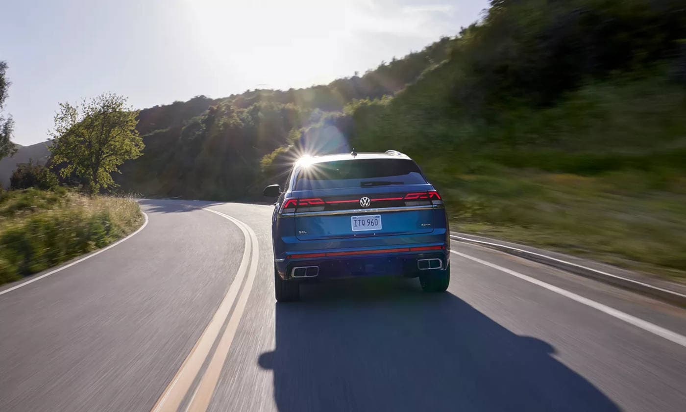 2024 Volkswagen Atlas Cross Sport driving through the mountains rear view