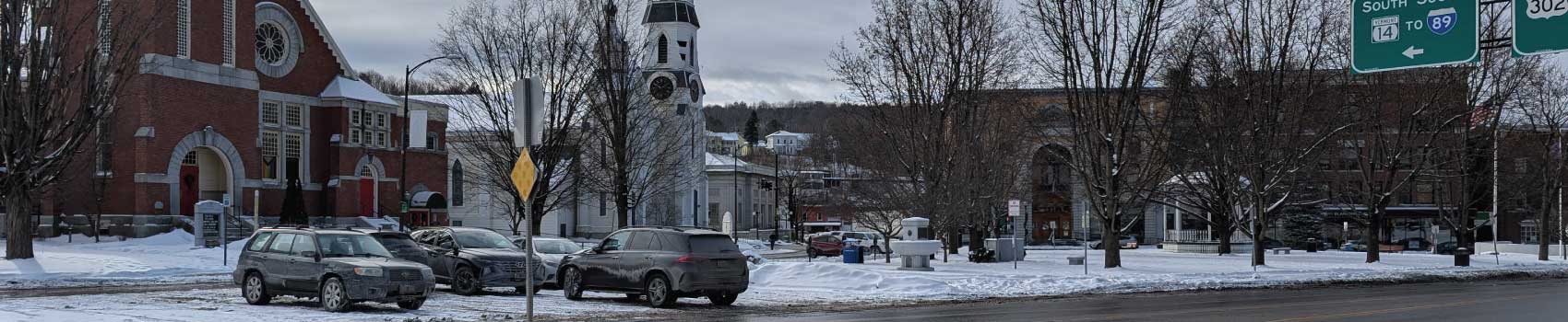 Used vehicles driving on snow-covered roads in Vermont near Montpelier with cars parked in the snow.