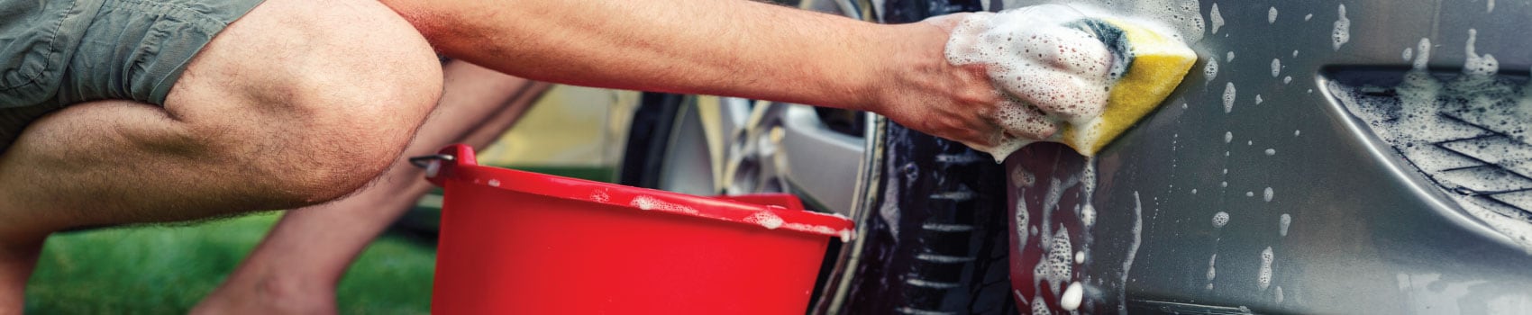 Vehicle owner cleaning car exterior before trade-in appraisal at Central Vermont Auto Mart in Montpelier Vermont
