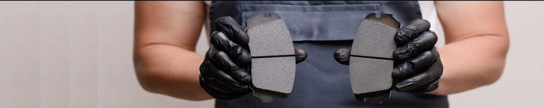 Ceramic-vs-Semi-Mettalic-Brake-Pads.jpg An automotive technician showing two different types of brake pads.