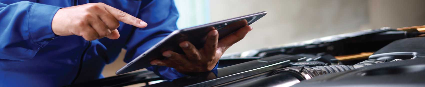 Technician performing a Vermont State Inspection on a vehicle using a tablet.
