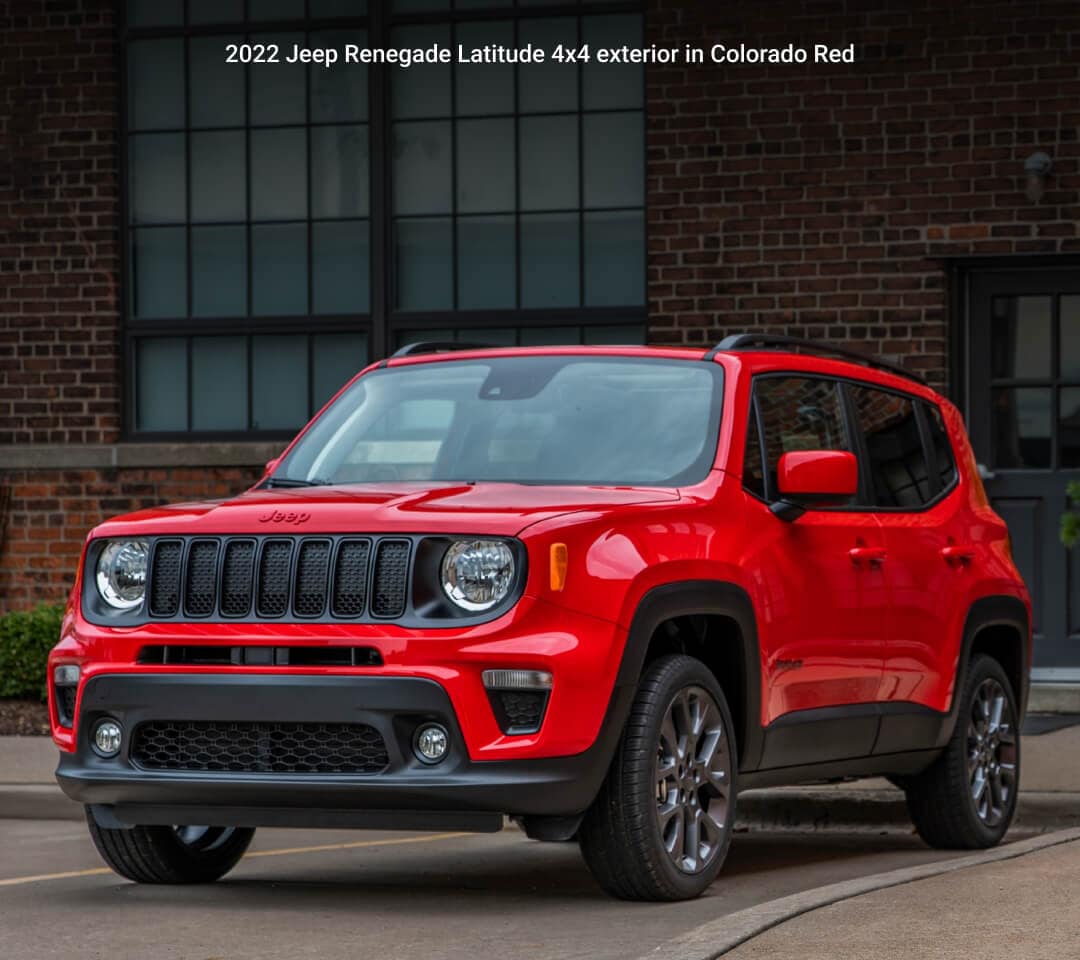 Front three-quarter view of 22 Jeep Renegade Latitude in Colorado Red stationary in front of a rustic brick building.