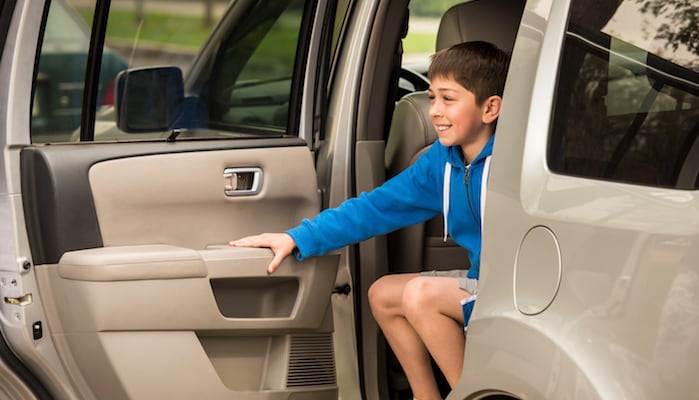 Boy getting out of back seat of parked SUV