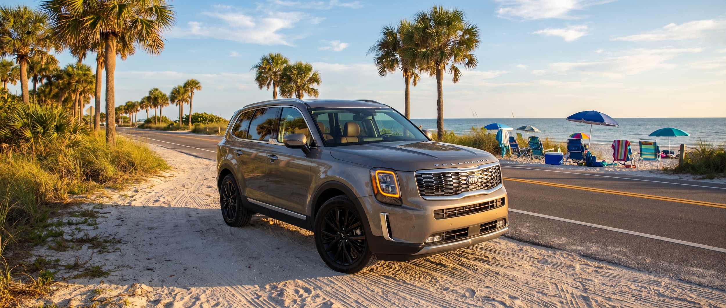 A 2022 Kia Telluride in a warm silver or gray finish parked near a Florida coastal road with palm trees and blue sky, family beach gear visible in the background, late-afternoon Gulf Coast light