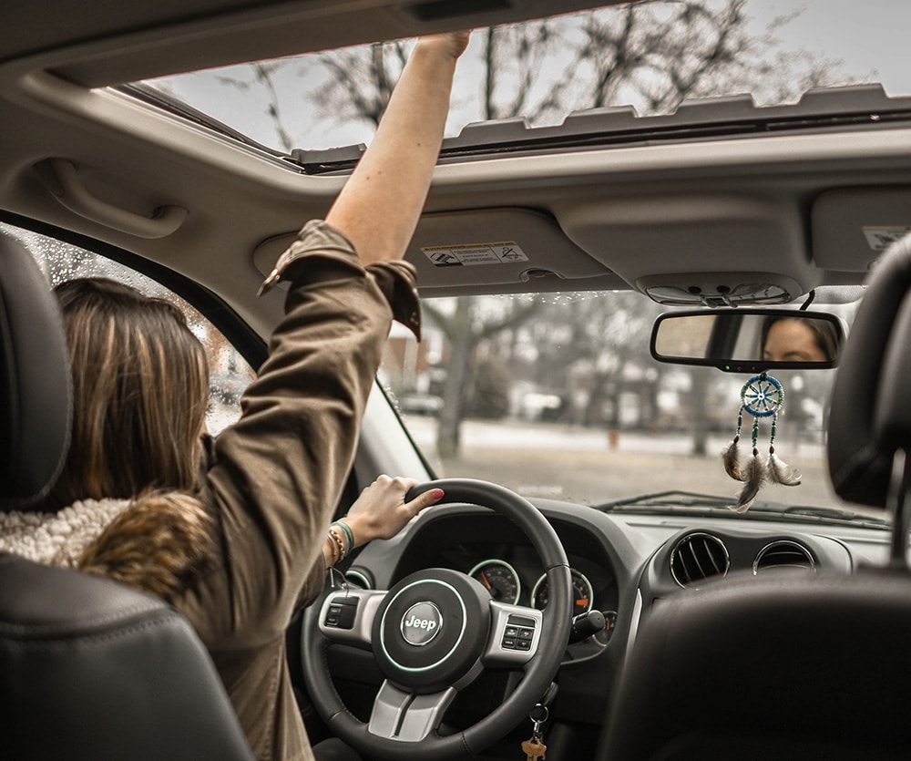 interior of vehicle woman driver with hand through moonroof_1.jpg