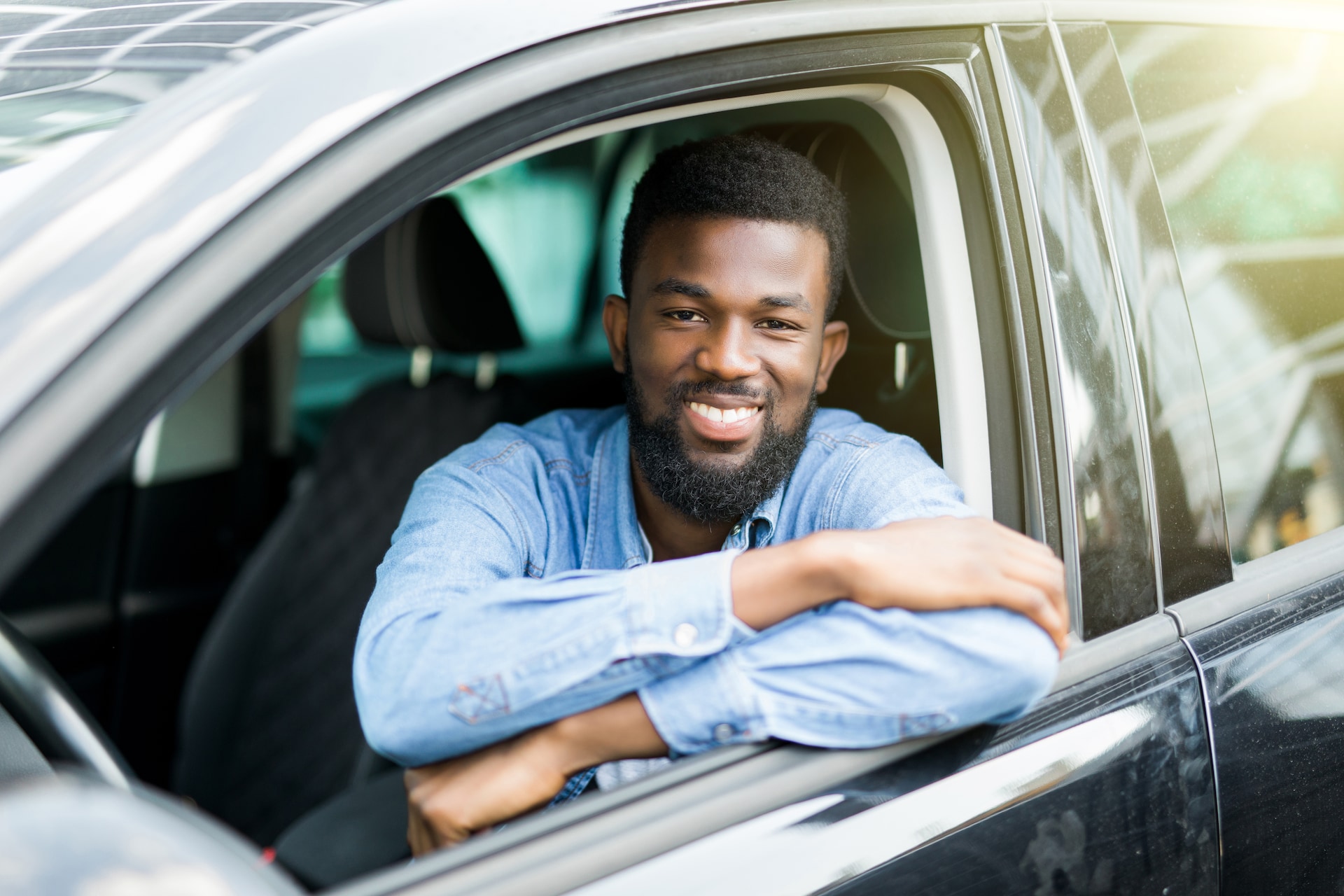 A person smiling in the driver's seat of a car A person smiling in the driver's seat of a car