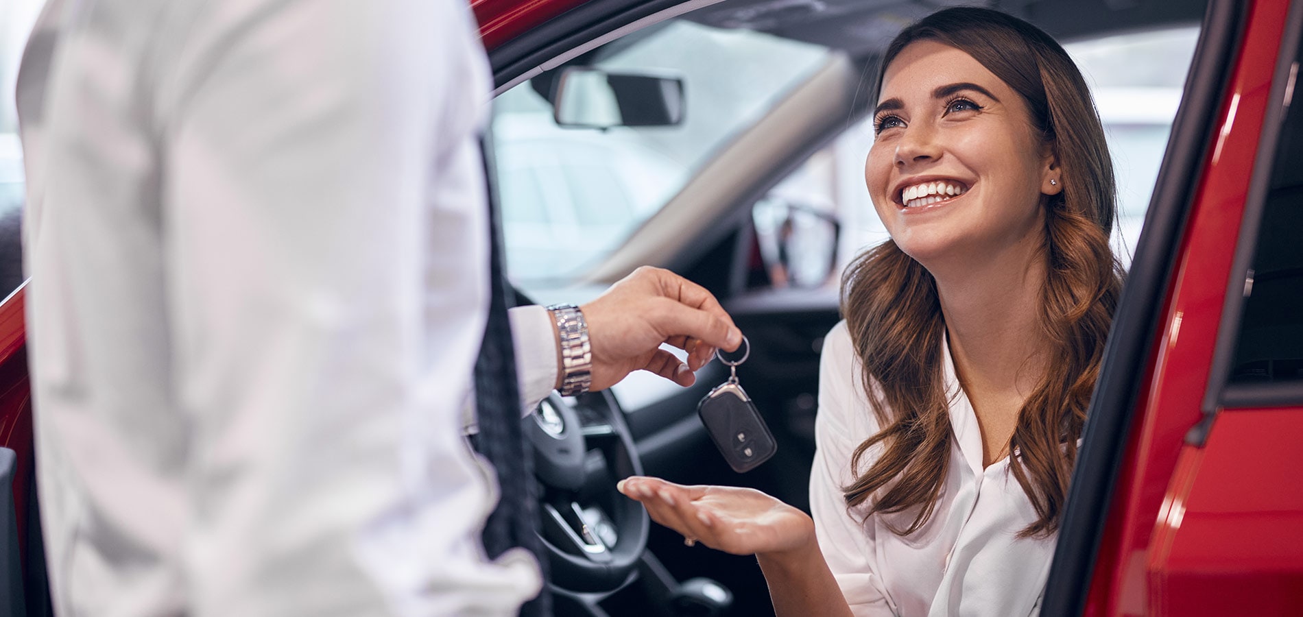 Young woman smiling as she's handed her new car's keys