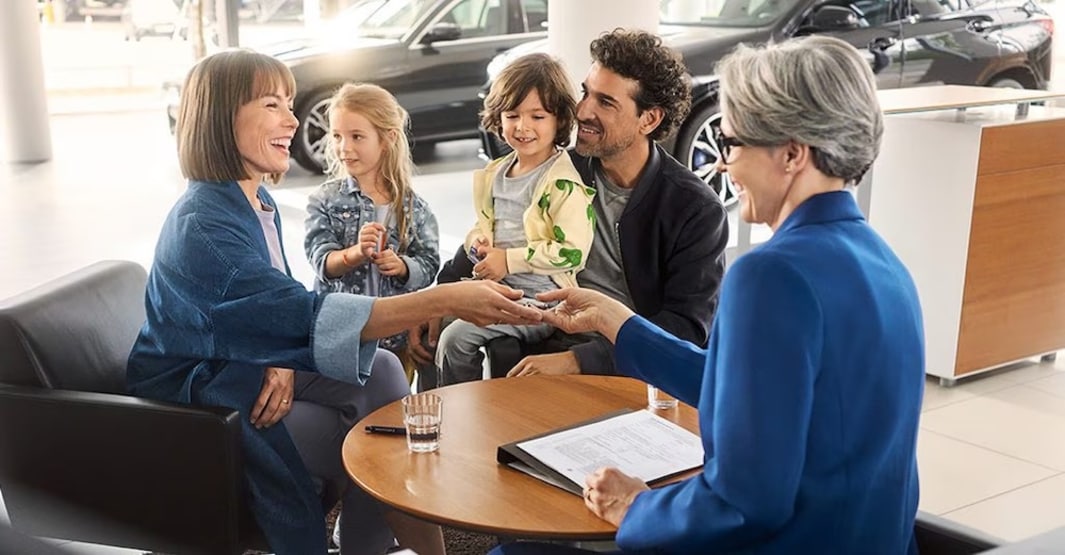 A finance advisor talking with a family of four inside a car dealership