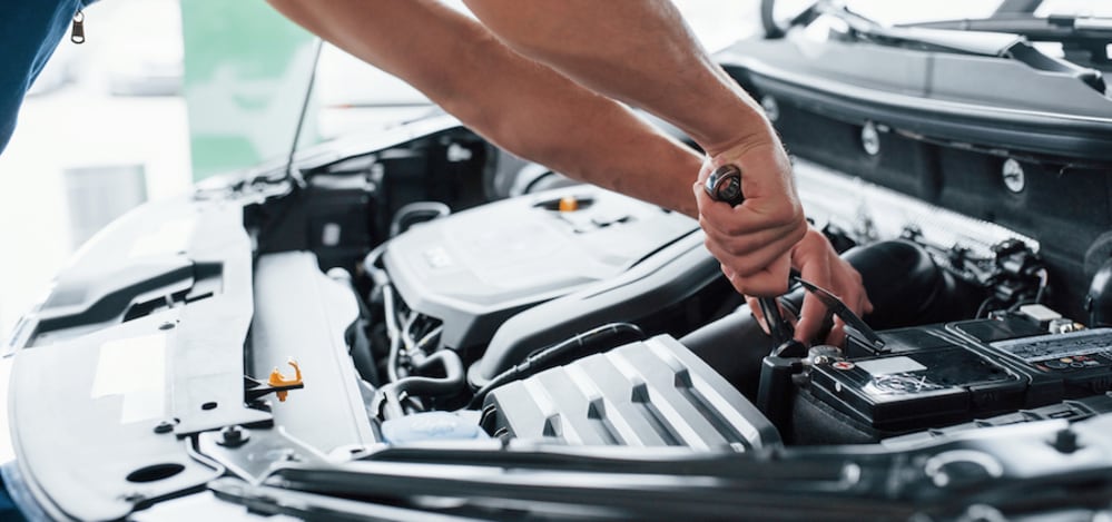 The arms of a white person working on a car engine