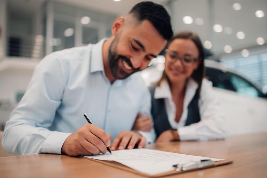 Two customers signing paperwork inside a car dealership