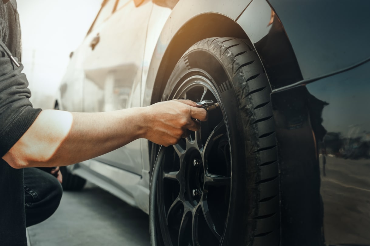The arm of a white person in a black clothes who is filling a tire with air 
