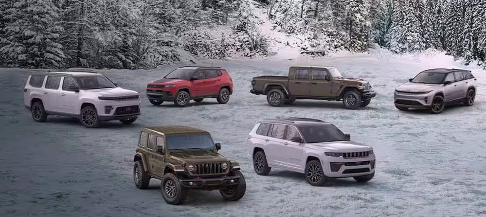 everal Jeep vehicles parked in a snowy field with pine trees in the background