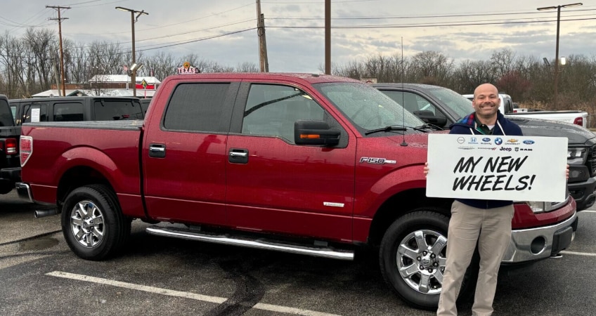 Person cheerfully posing in front of his new ram truck