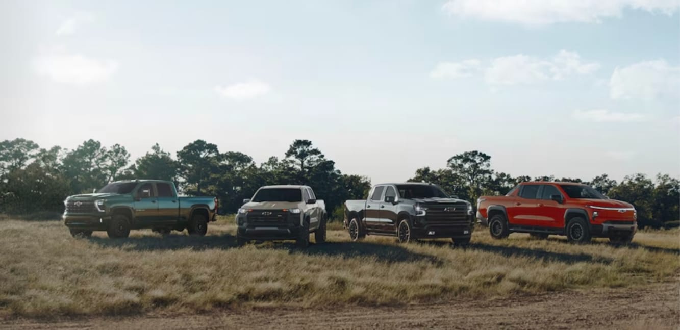 Four Chevrolet pickup trucks parked in a field