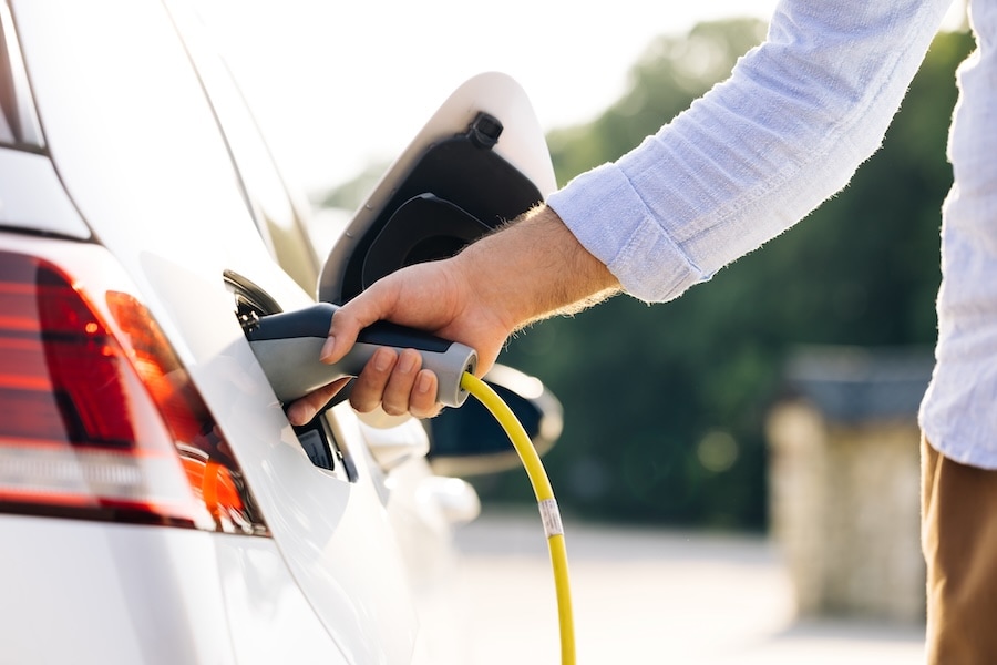 A driver charging a white plug-in hybrid vehicle