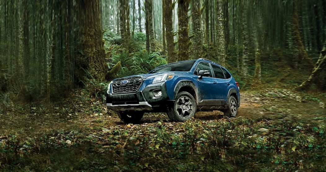 A blue 2026 Subaru Forester driving through a forest