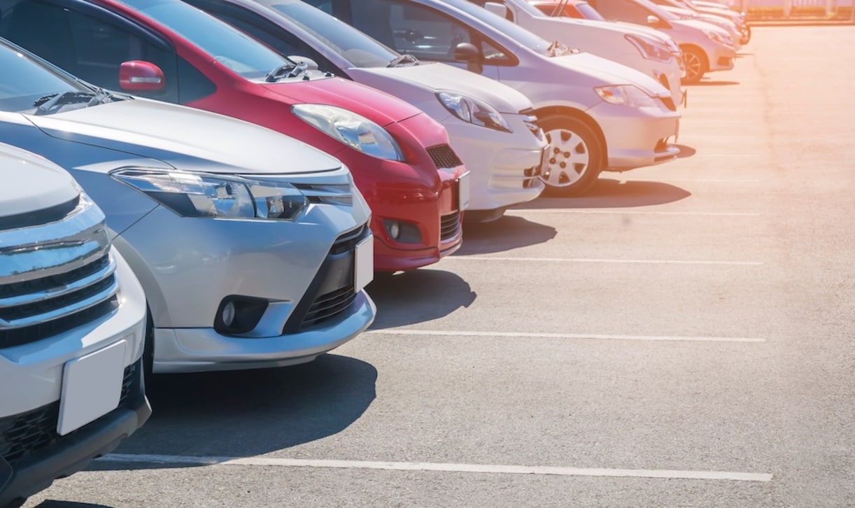 The hoods of several used cars parked in a used car dealership lot