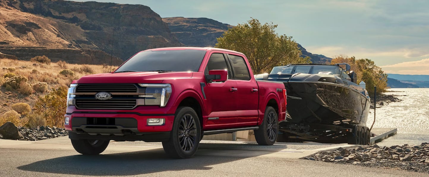 A red 2026 Ford F-150 truck towing a boat out of a body of water