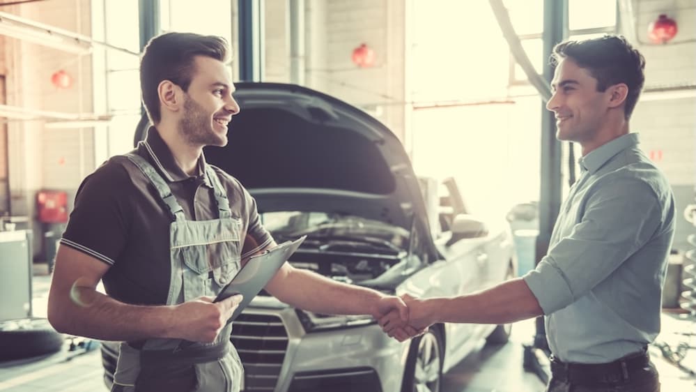 A mechanic shaking hands with a customer in a vehicle service center