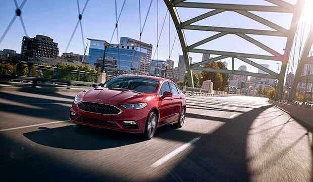 car driving across bridge; red 2018 Ford Fusion