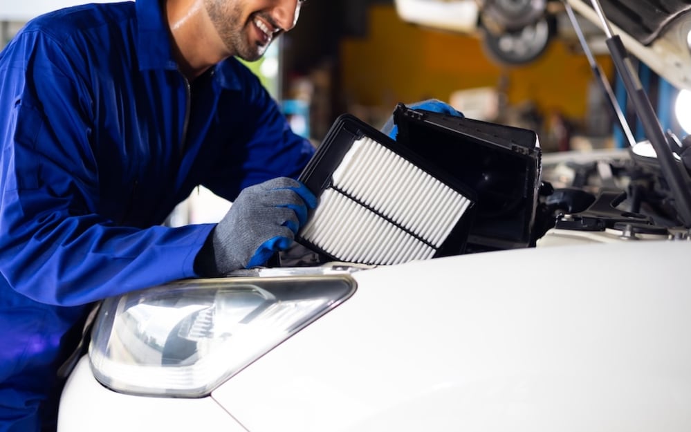 A service technician replacing a filter in a vehicle's engine