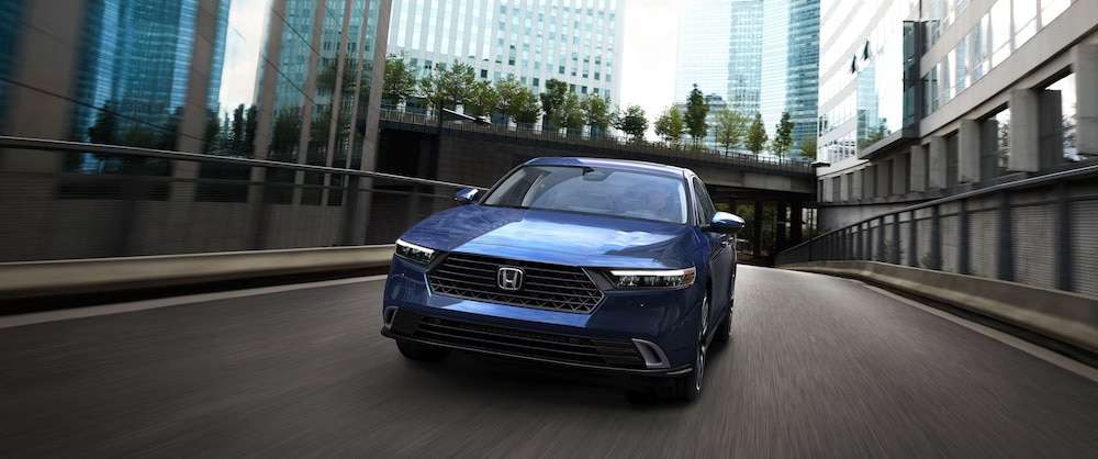 The front of a dark blue 2025 Honda Accord sedan driving down a city street