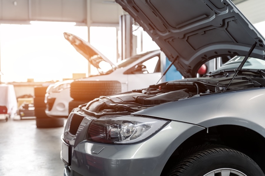 Two cars with their hoods open in a vehicle service center