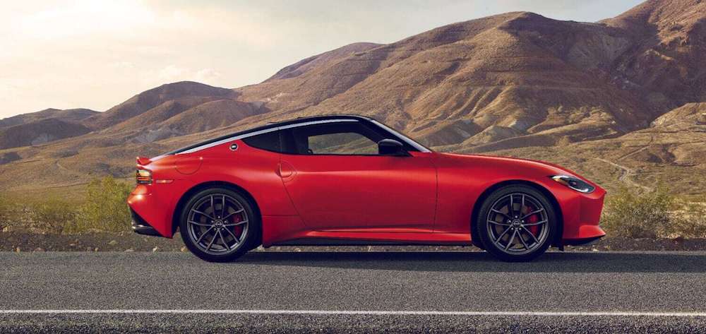 A side view of a red 2025 Nissan Z driving down a road