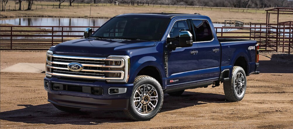 A dark blue Ford F-250 pickup truck parked in front of a paddock