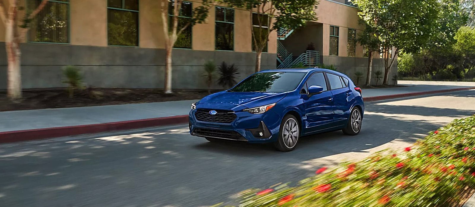 Blue 2026 Subaru Impreza driving by an apartment building