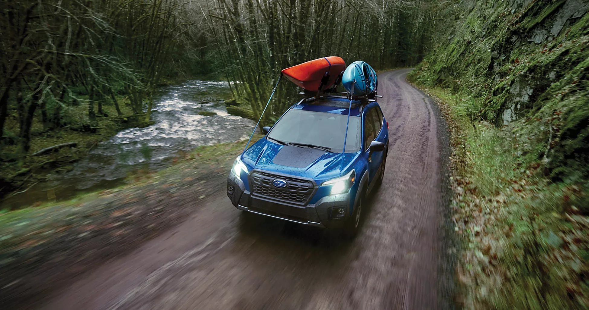 Blue 2024 Subaru Forester driving through the woods