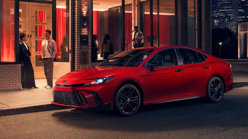 A red 2026 Toyota Camry sedan parked in front of a music venue at night