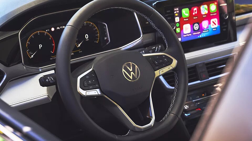 The steering wheel of a 2025 Volkswagen Taos, with an illuminated touch screen beside it