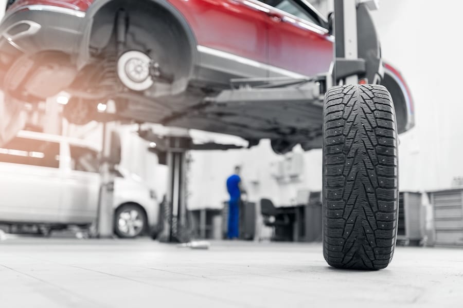 A car on a lift in a service center, its tires being replaced